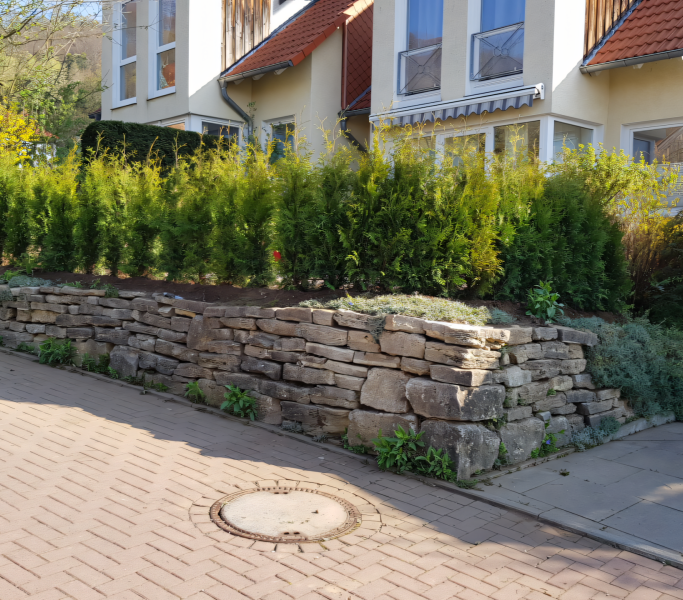 Vorderansicht eines Hauses mit einer Mauer aus Natursteinen
